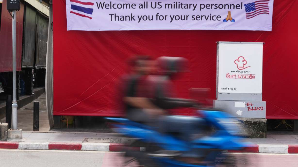 A motorcycle taxi drives past a banner in Pattaya, Thailand, Tuesday. The USS Abraham Lincoln aircraft carrier docked at a port in eastern Thailand on Tuesday after its grueling deployment in the Middle East.