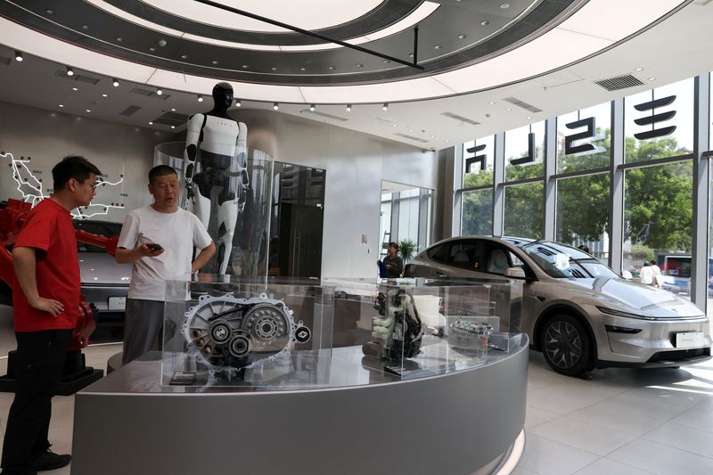 FILE PHOTO: A staff member attends to a customer inside a Tesla store at a shopping mall, in Beijing, China, May 12, 2026.