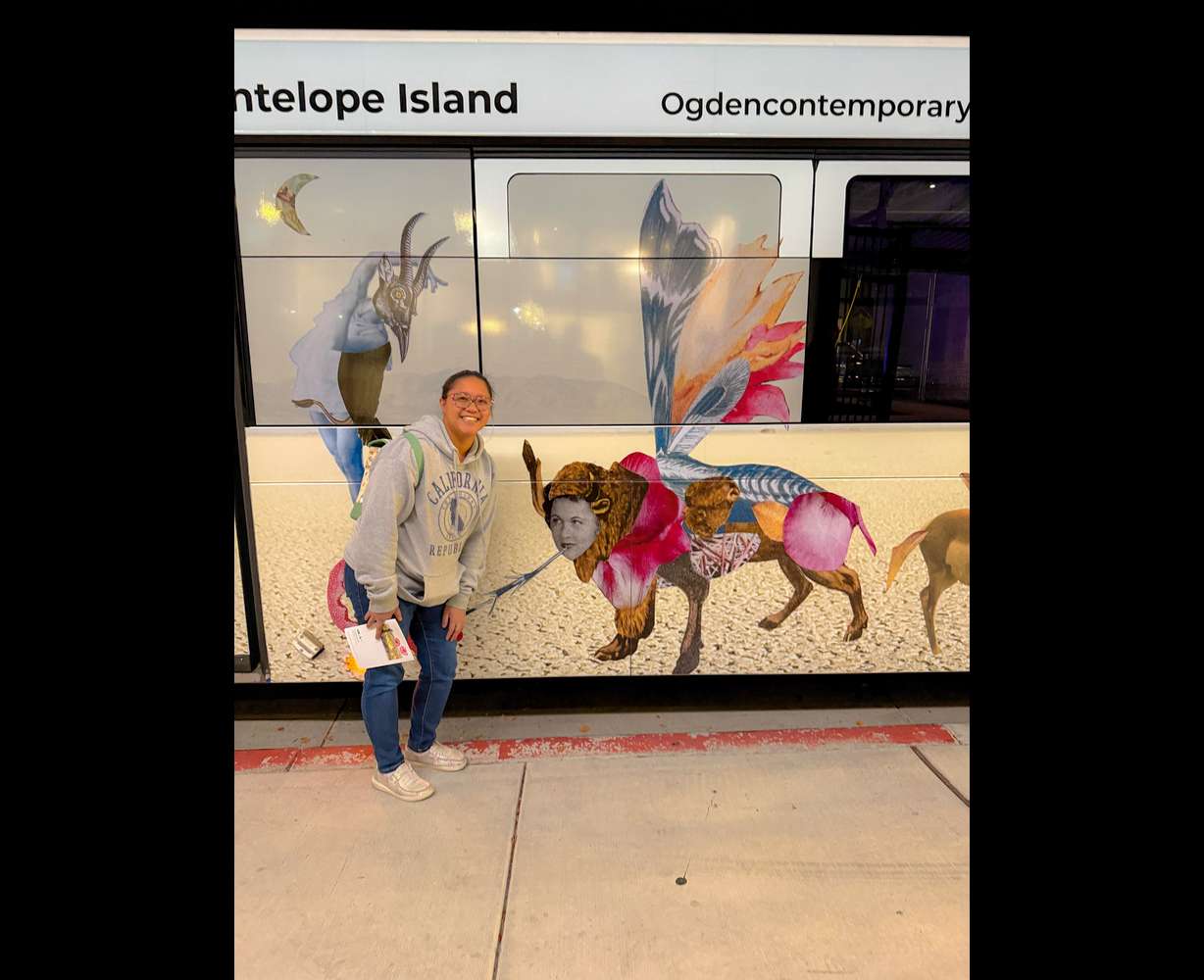 Tawni Jae Sherlock poses next to her painting, "Betsy," as it's displayed on the side of a public bus in Ogden.