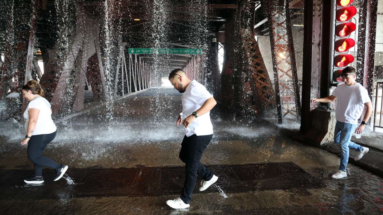 People scamper west across the lower level of the DuSable Lake Shore Drive bridge over the Chicago River on Wednesday, Sept. 2, 2026, as water pumped by a Chicago Fire Department boat flows down onto the double-leaf, double-deck, fixed counterweight bridge.