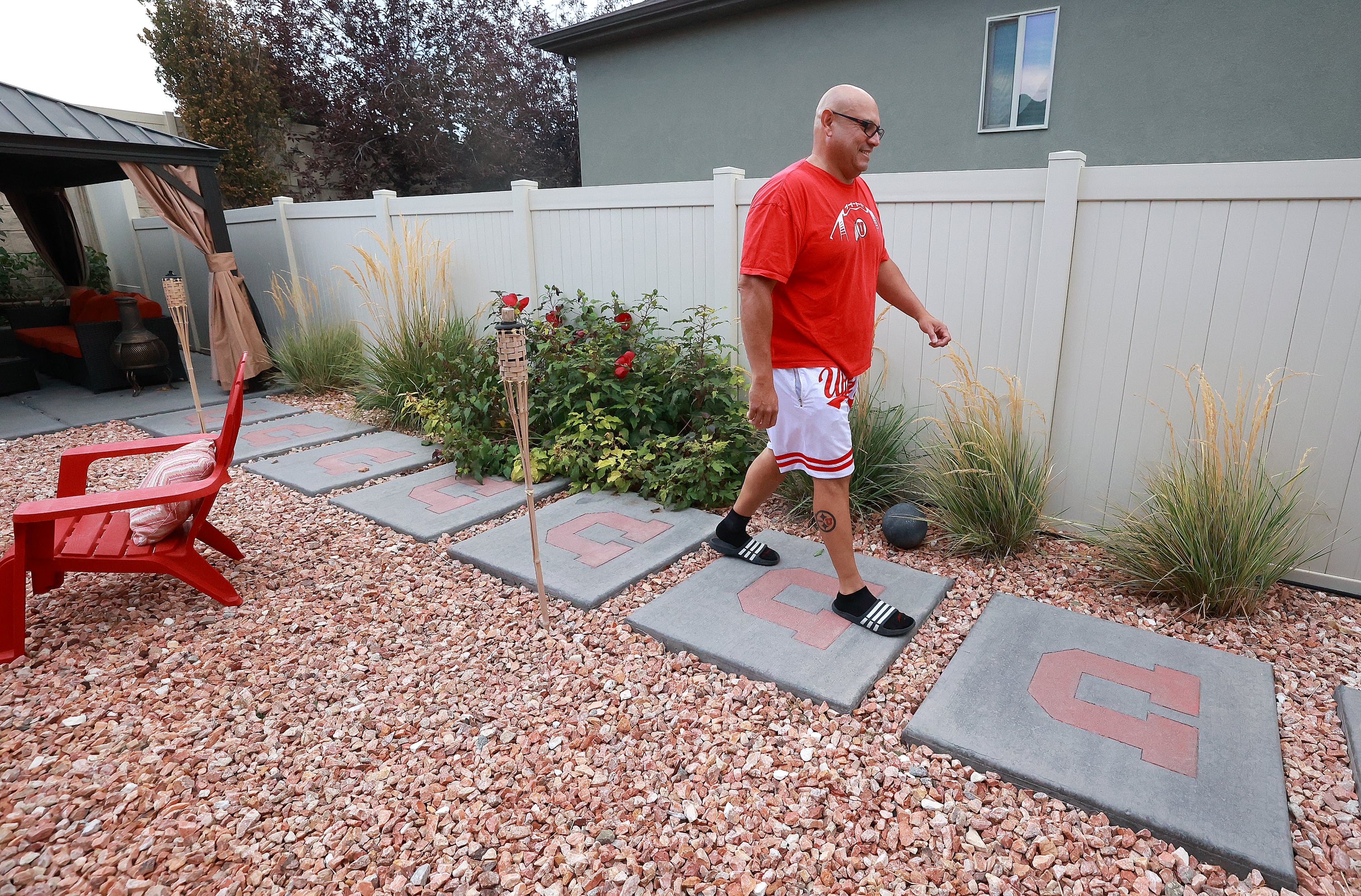 University of Utah football superfan Albert Gamboa walks along U stepping stones as he shows some of the many University of Utah-themed decorations around his house in Riverton on Aug. 24.