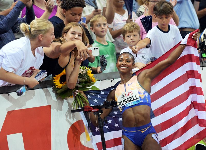 FILE PHOTO: Athletics - Diamond League - Zurich - Letzigrund, Zurich, Switzerland - August 27, 2026 Masai Russell of the U.S. poses for selfies with spectators after winning the women's 100m hurdles final and setting a new world record