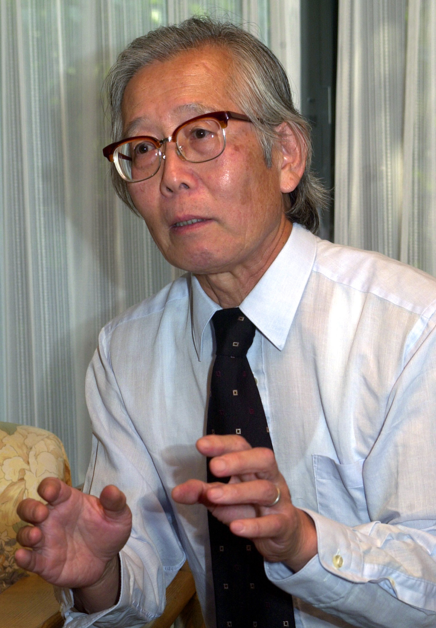 FILE - Japanese Nobel Prize winner, chemist Hideki Shirakawa, speaks with Swedish Embassy Minister Karl Leifland at his home in Yokohama, south of Tokyo, on Oct. 11, 2000. 