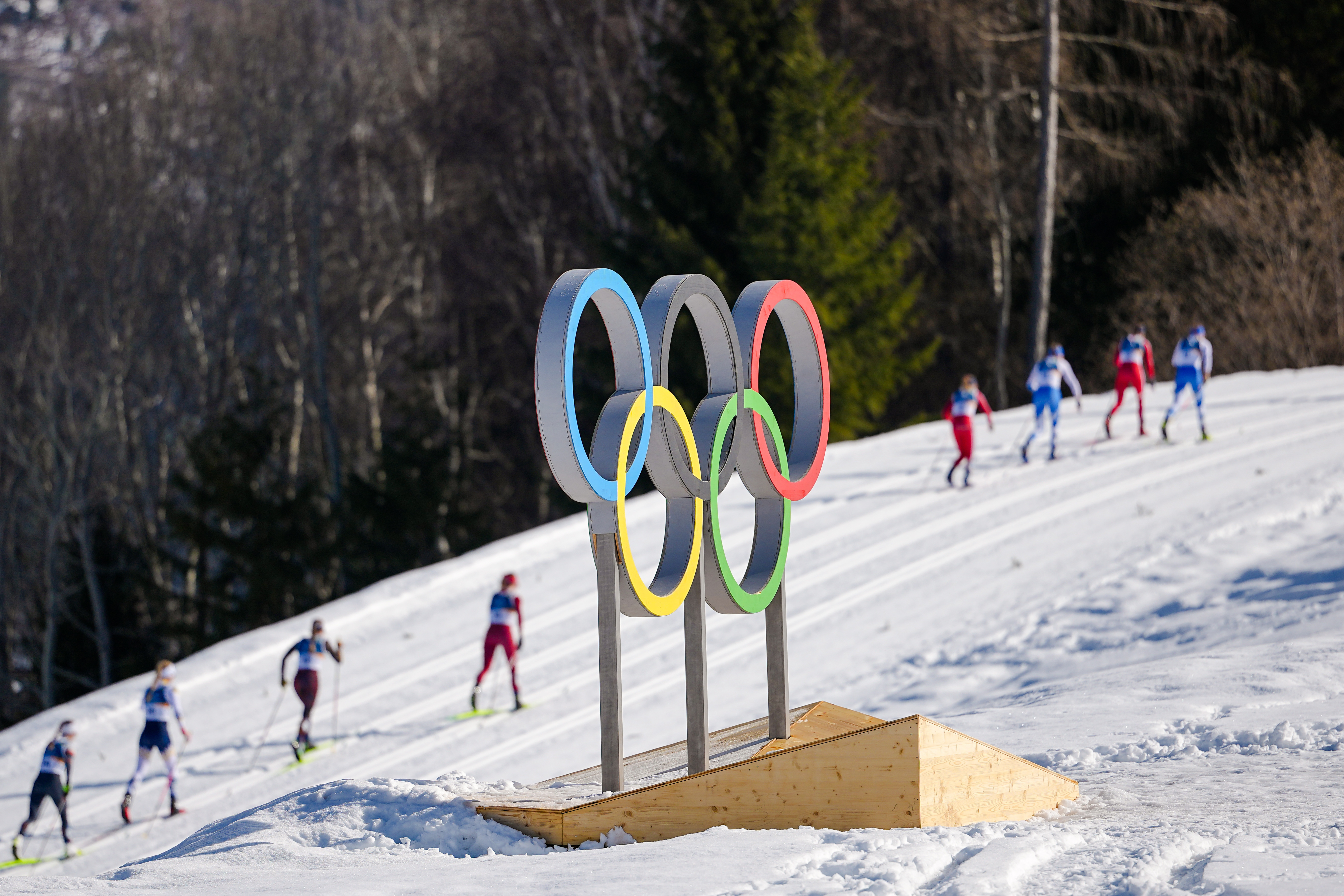 FILE - Athletes ski past the Olympic rings during the cross country skiing women's 50km mass start classic at the 2026 Winter Olympics, in Tesero, Italy, Feb. 22, 2026. 