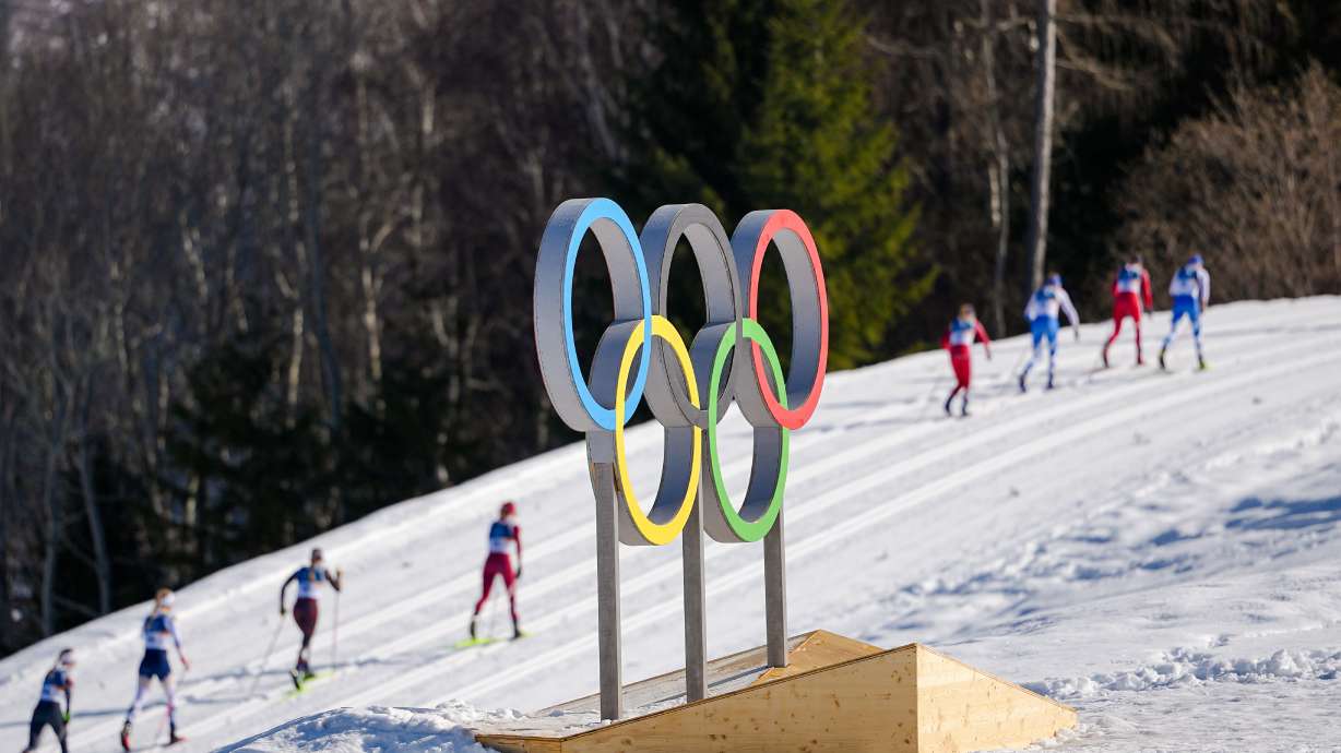 FILE - Athletes ski past the Olympic rings during the cross country skiing women's 50km mass start classic at the 2026 Winter Olympics, in Tesero, Italy, Feb. 22, 2026.
