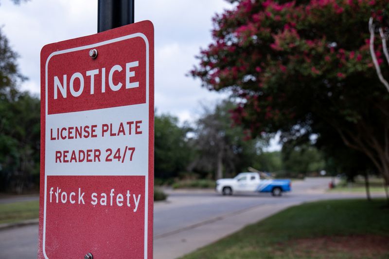 A sign describes a Flock camera as a 24/7 license plate reader near a retail area in Sun Valley, Texas, July 31.