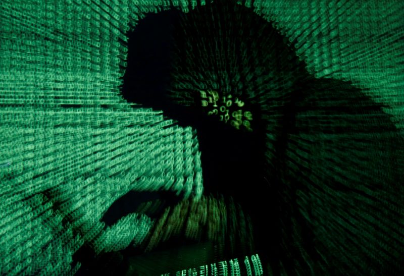 FILE PHOTO: A man holds a laptop computer as cyber code is projected on him in this illustration picture taken on May 13, 2017.