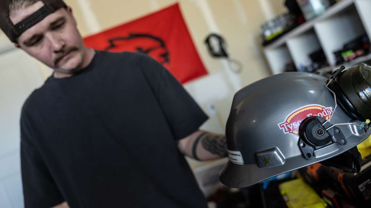 Austin Campbell holds up his Tyson Foods hard hat in his home in Eagle Mountain on Tuesday. Campbell is one of many Utahns who have been bitten by a large wave of layoffs.