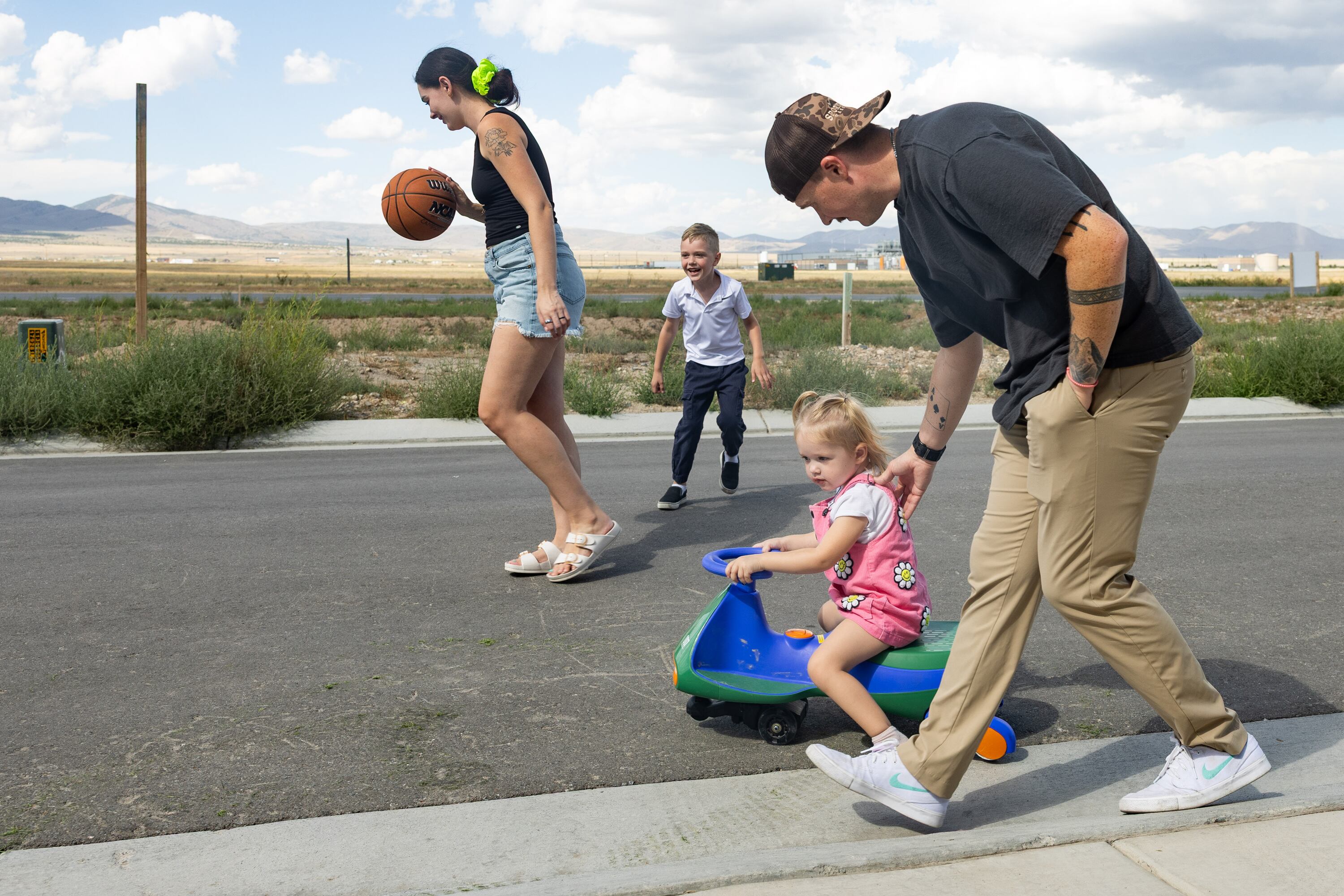 Austin Campbell pushes his daughter Piper on her tricycle while his wife, Jessi, plays basketball with their son Quinn near their home in Eagle Mountain on Tuesday. Austin Campbell recently was laid off from his job.