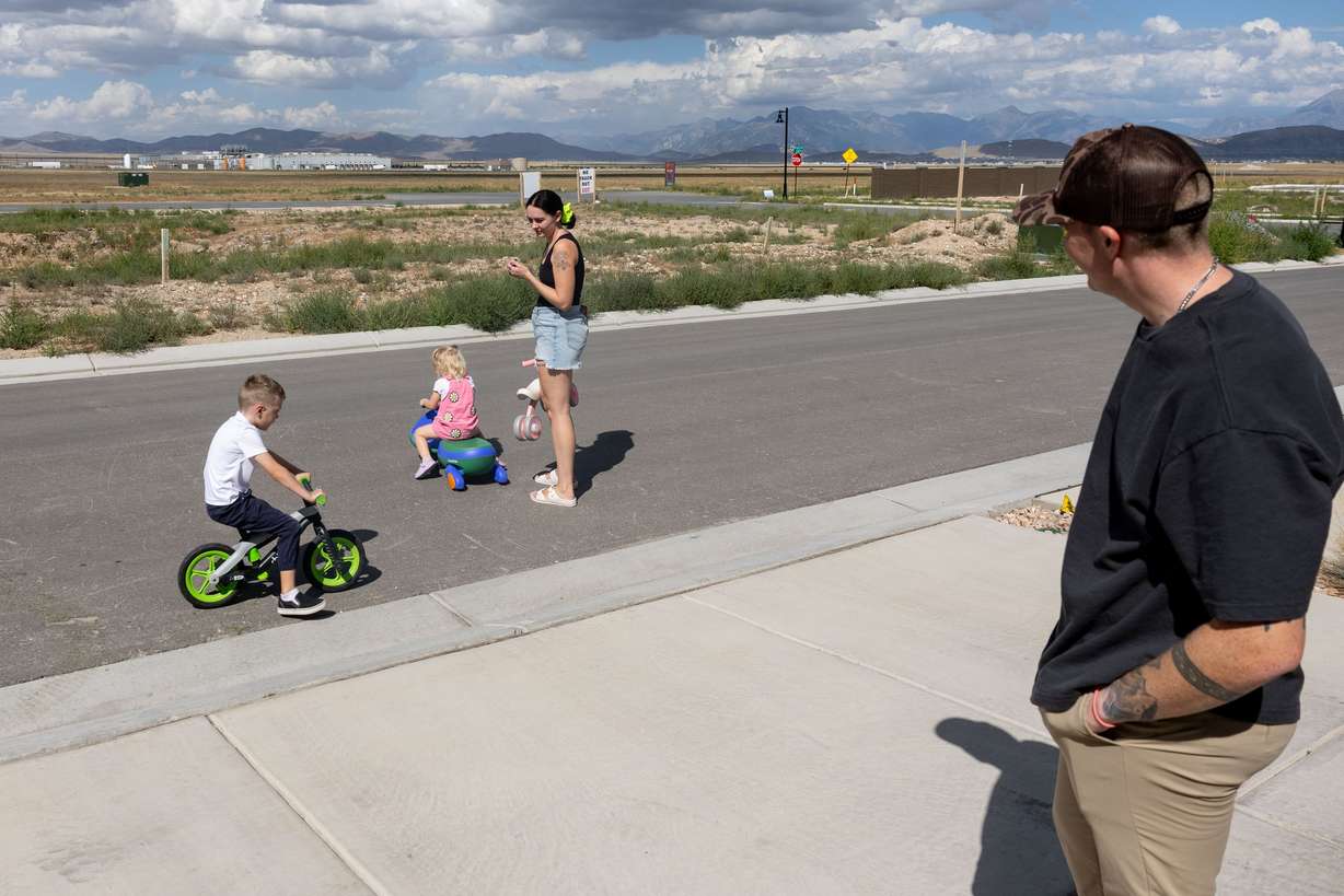 Austin Campbell watches his wife, Jessi, play with their two children, Quinn and Piper, near their home in Eagle Mountain on Tuesday. The Tyson Food plant seen behind his family announced its October closure three weeks ago, leaving Austin Campbell 60 days to find work elsewhere.