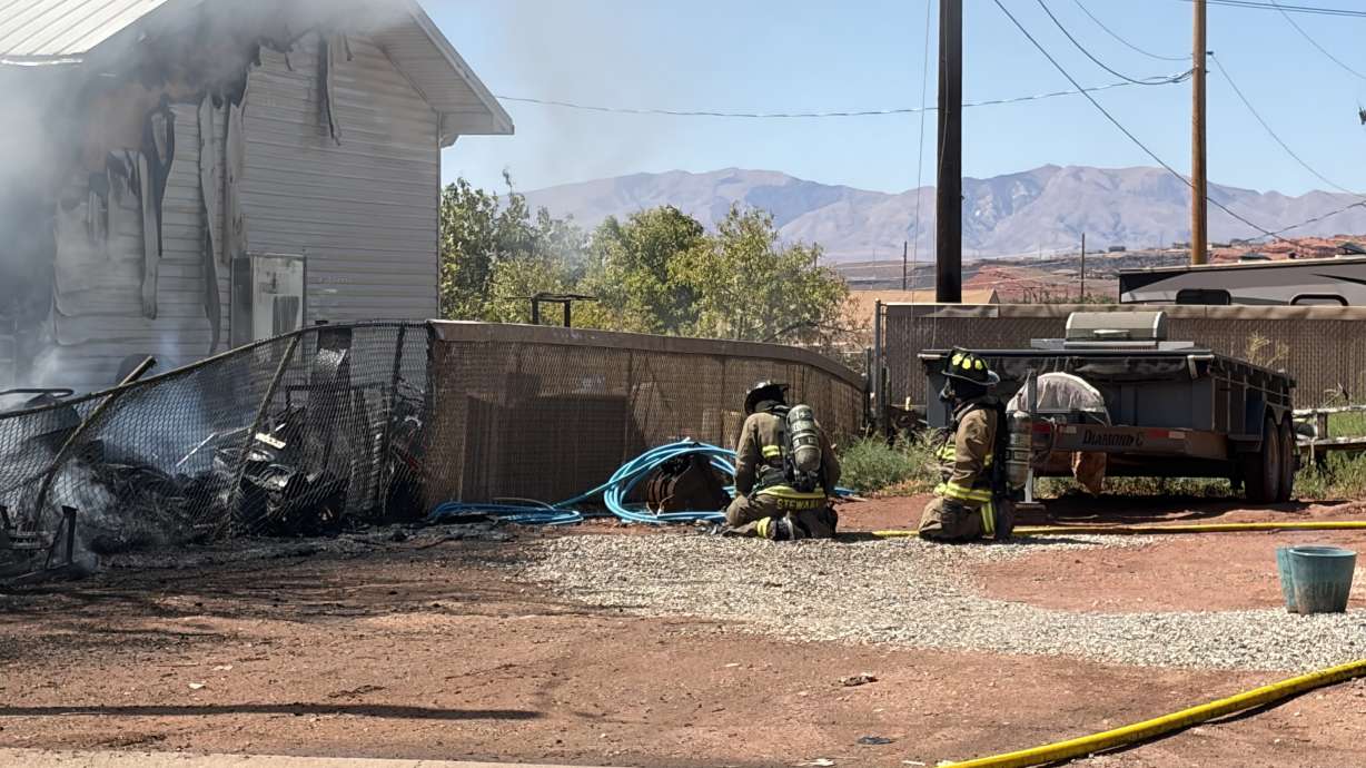 Firefighters kneel next to a house in Washington, Washington County, that caught fire on Friday.