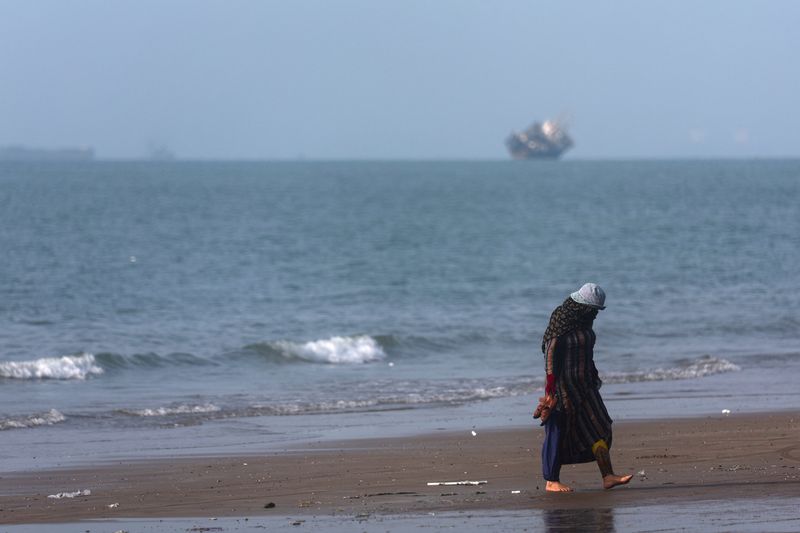 A woman walks on the beach of Bandar Abbas with vessels in the Strait of Hormuz, Iran, on Saturday.