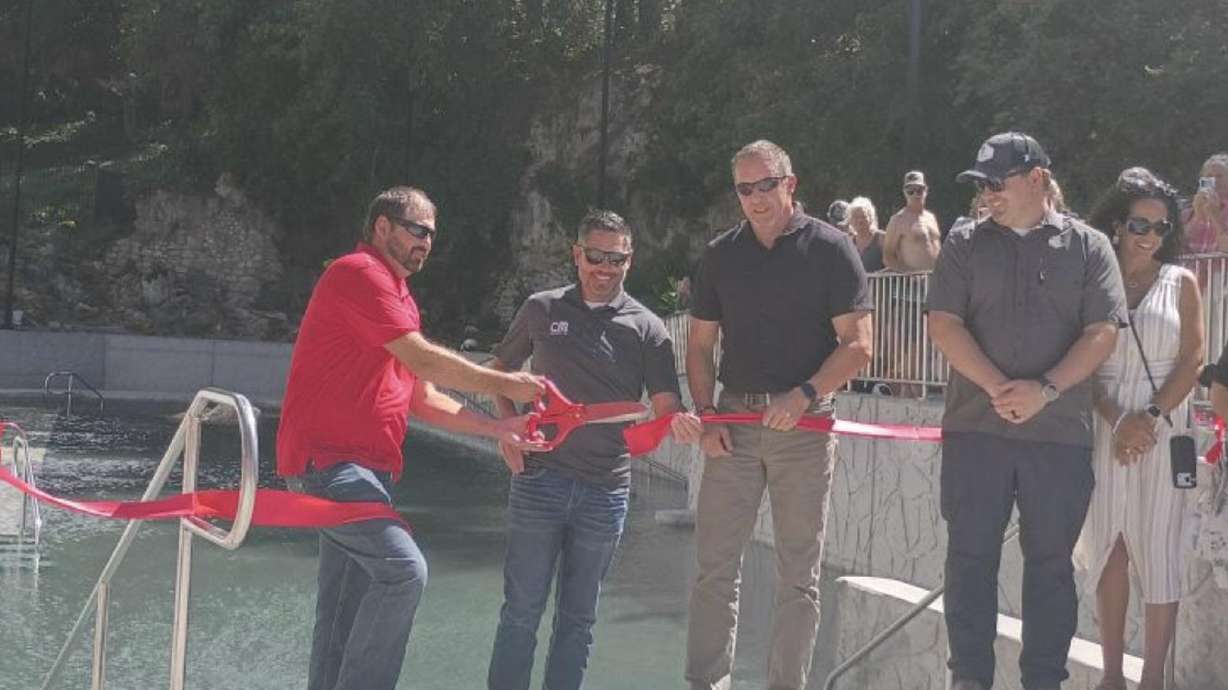 Lava Hot Springs Foundation executive director Tyson Koester cuts the ribbon on the newly renovated hot pool Thursday as local officials look on.