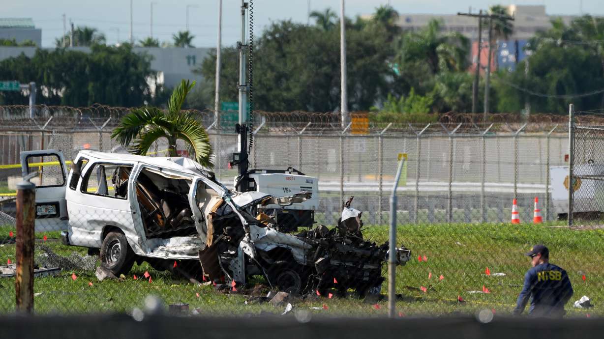 An NTSB investigator works near a damaged van at the site where an Amazon cargo plane overshot the runway two days earlier while landing at Miami International Airport, Tuesday. The five people killed in the crash were inside a van used by plane cleaners, authorities said.