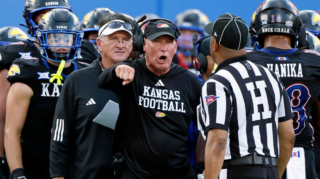 FILE - Kansas head coach Lance Leipold, center, disputes a call by an official during the first half of an NCAA collage football game against West Virginia Sept. 20, 2025, in Lawrence, Kan.
