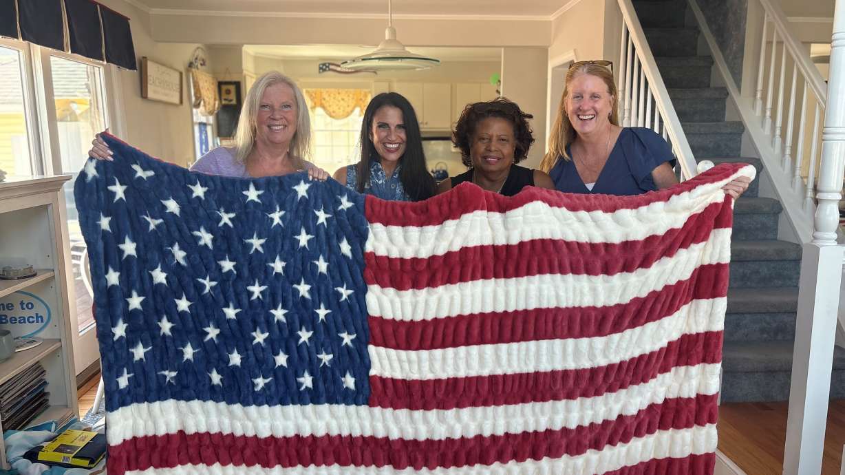 Carrie Pike in New York City stands with three women on Tuesday who lost their firefighter husbands on 9/11, holding a donated Minky Couture American Flag blanket