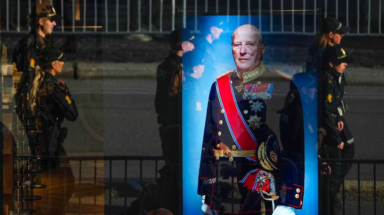 Police officers reflected in a window with a display showing Norway's late King Harald V prior to his funeral in Oslo, Norway, Wednesday. Thousands gathered to bid a final farewell to Harald.