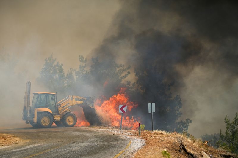 A forest worker operates an excavator to battle a wildfire in Cine in the southwestern Aydin province, Turkey, July 31, 2026.