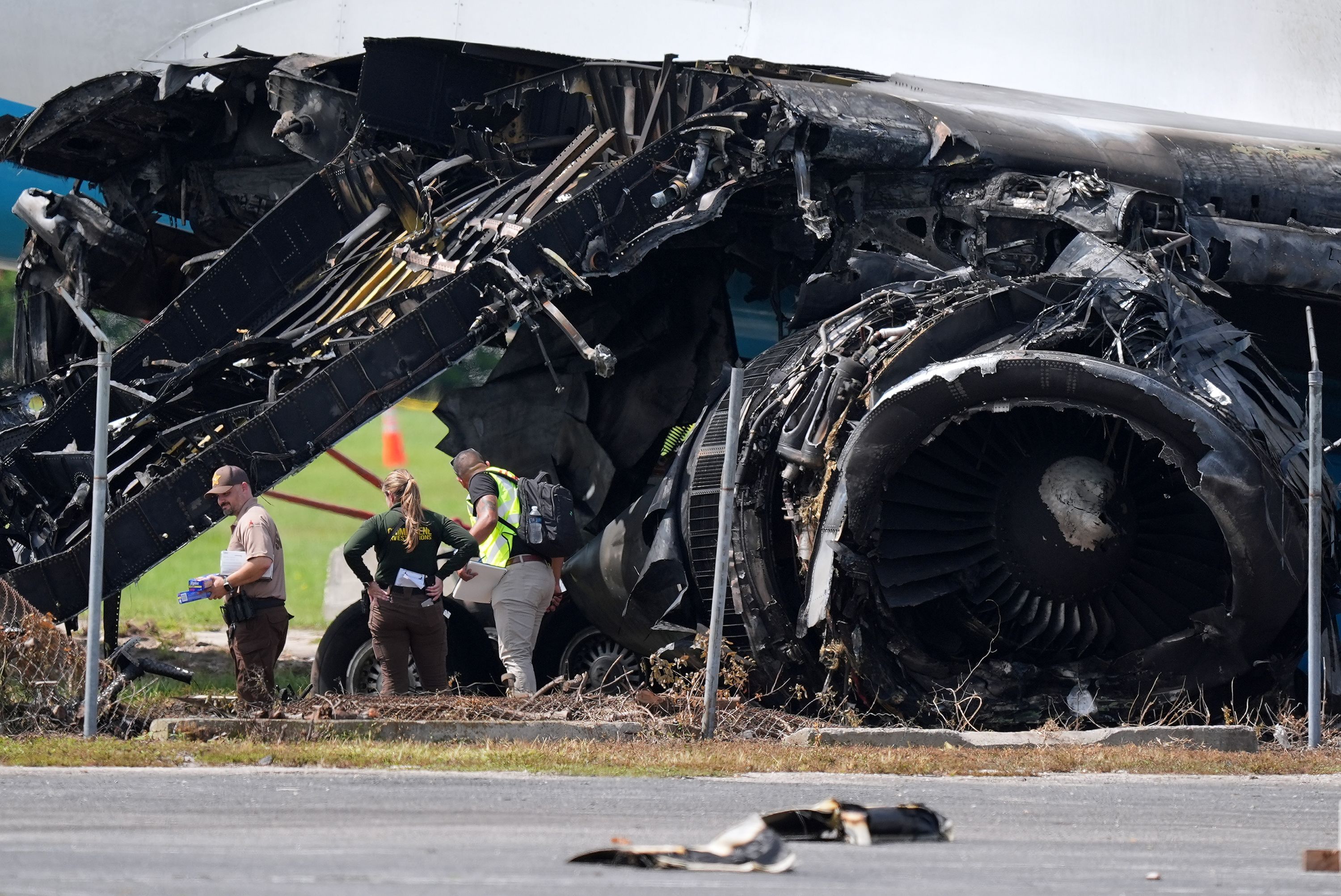 Authorities stand near a destroyed wing and engine on September 8th as they work the scene of Sunday's Amazon cargo plane crash.