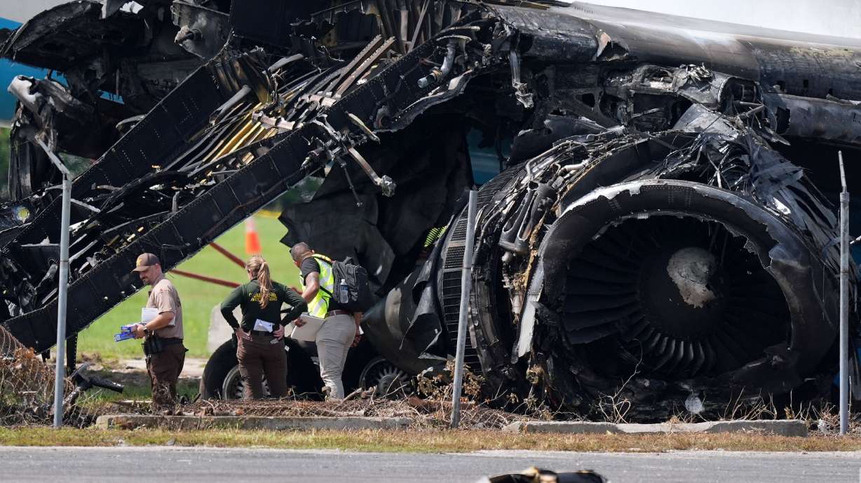 Authorities stand near a destroyed wing and engine on September 8th as they work the scene of Sunday's Amazon cargo plane crash.