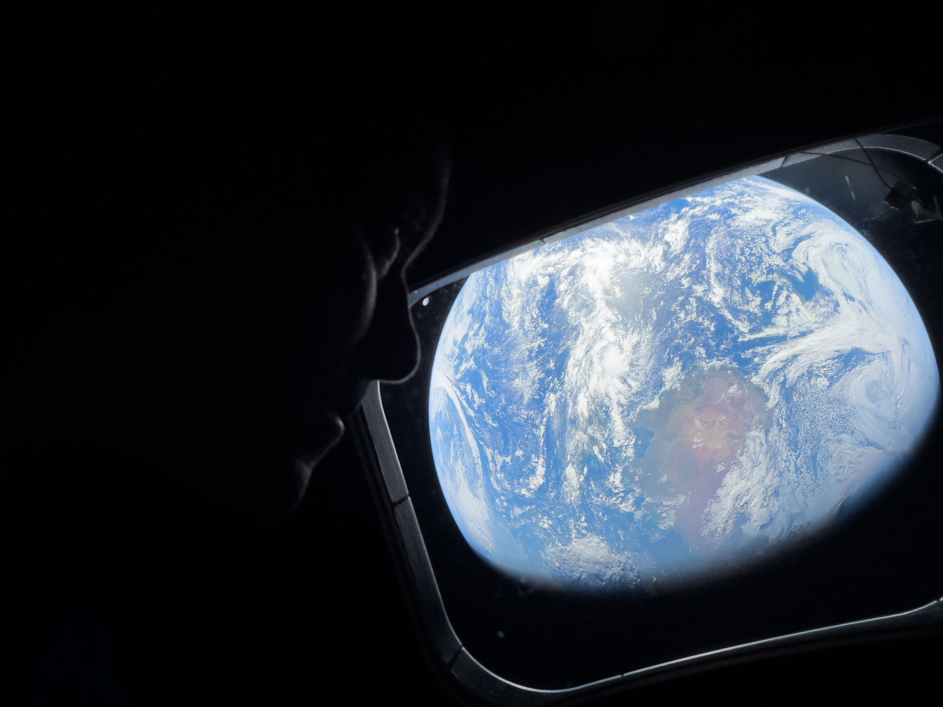 NASA astronaut and Artemis II Commander Reid Wiseman peers out of one of the Orion spacecraft's main cabin windows, looking back at Earth, as the crew travels towards the Moon on April 4, 2026. NASA's Artemis II mission will take Wiseman, Glover, Koch, and Hansen on a 10-day journey around the Moon and back aboard their Orion spacecraft.