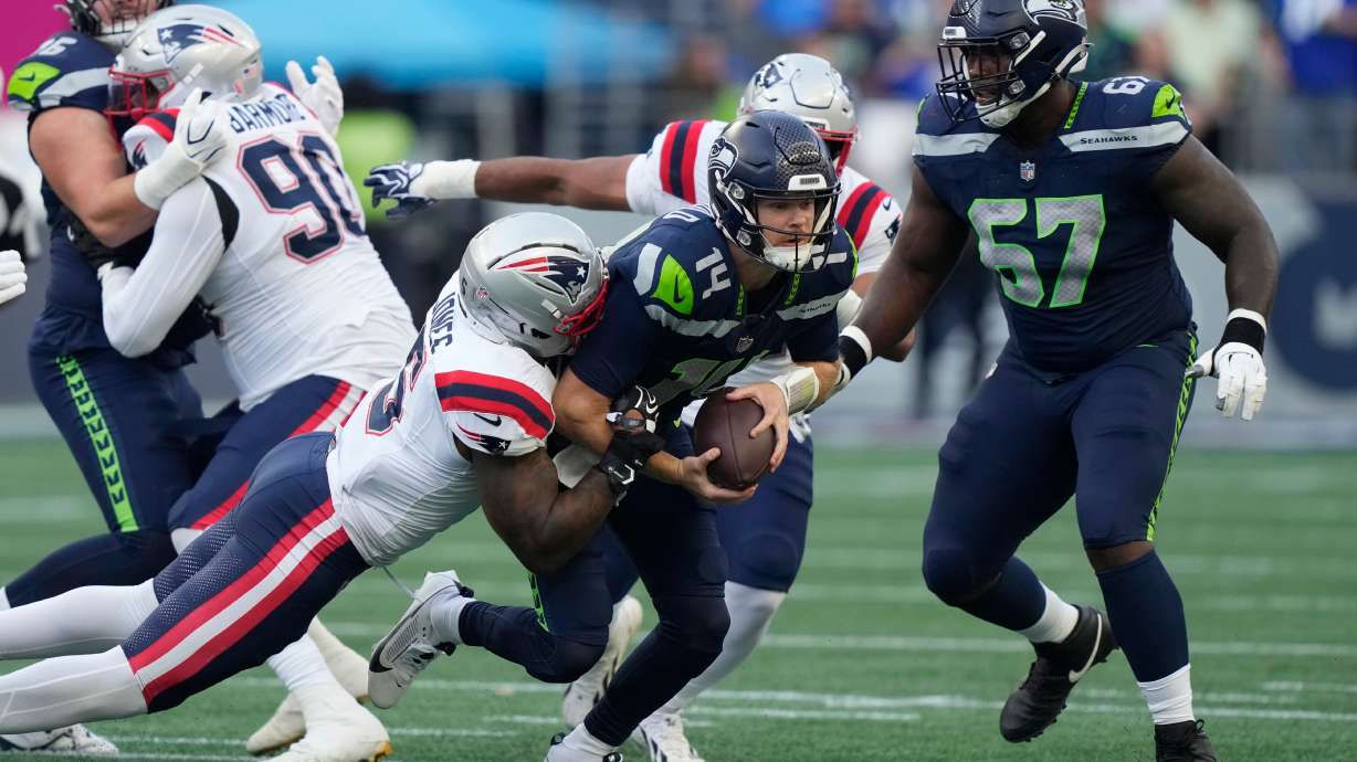 Seattle Seahawks quarterback Sam Darnold, center, is sacked by New England Patriots linebacker Dre'mont Jones, left, as Seattle Seahawks linebacker Connor O'Toole is at right, during the first half of an NFL football game, Wednesday, Sept. 9, 2026, in Seattle.