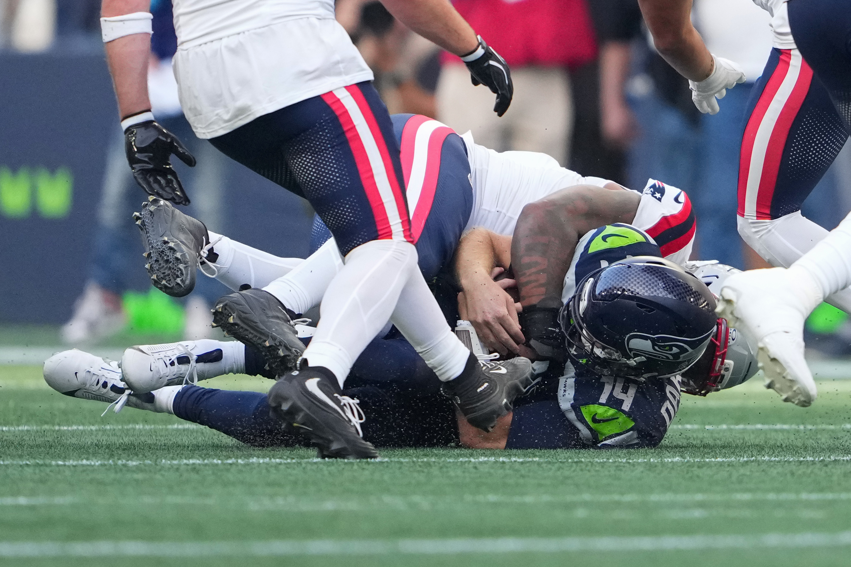Seattle Seahawks quarterback Sam Darnold, (14) is sacked by New England Patriots linebacker Dre'mont Jones, behind, during the first half an NFL football game, Wednesday, Sept. 9, 2026, in Seattle. 