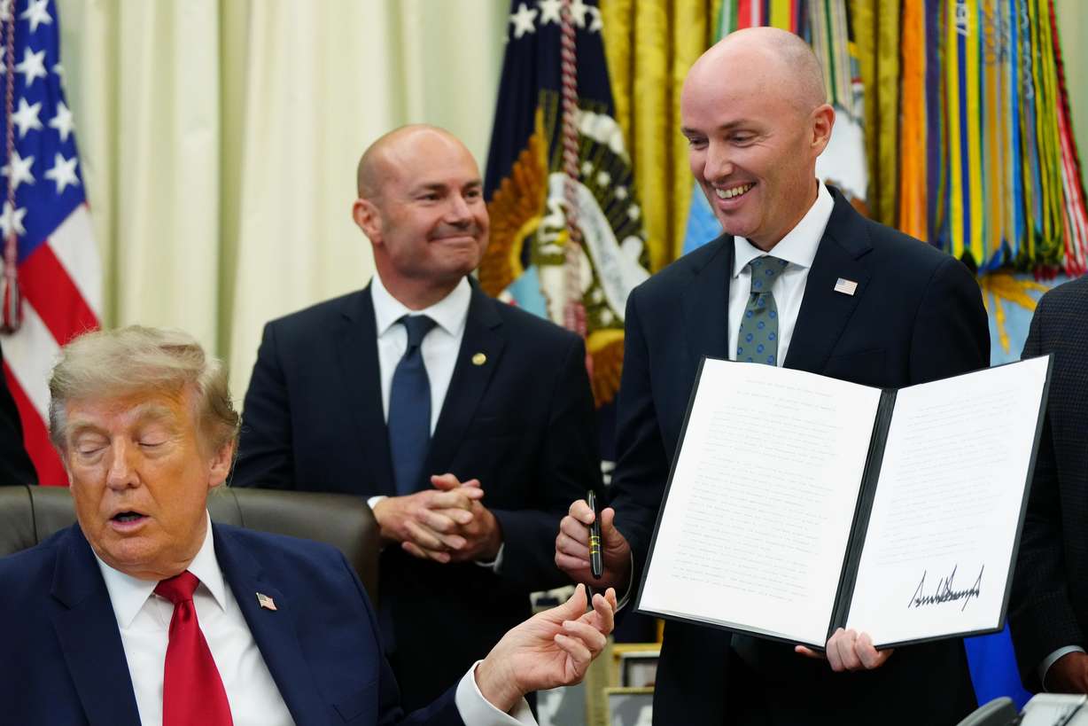 President Donald Trump hands a pen to Utah Gov. Spencer Cox after signing executive orders modifying the Grand Staircase-Escalante National Monument and the Bears Ears National Monument in the Oval Office of the White House, July 13, in Washington.