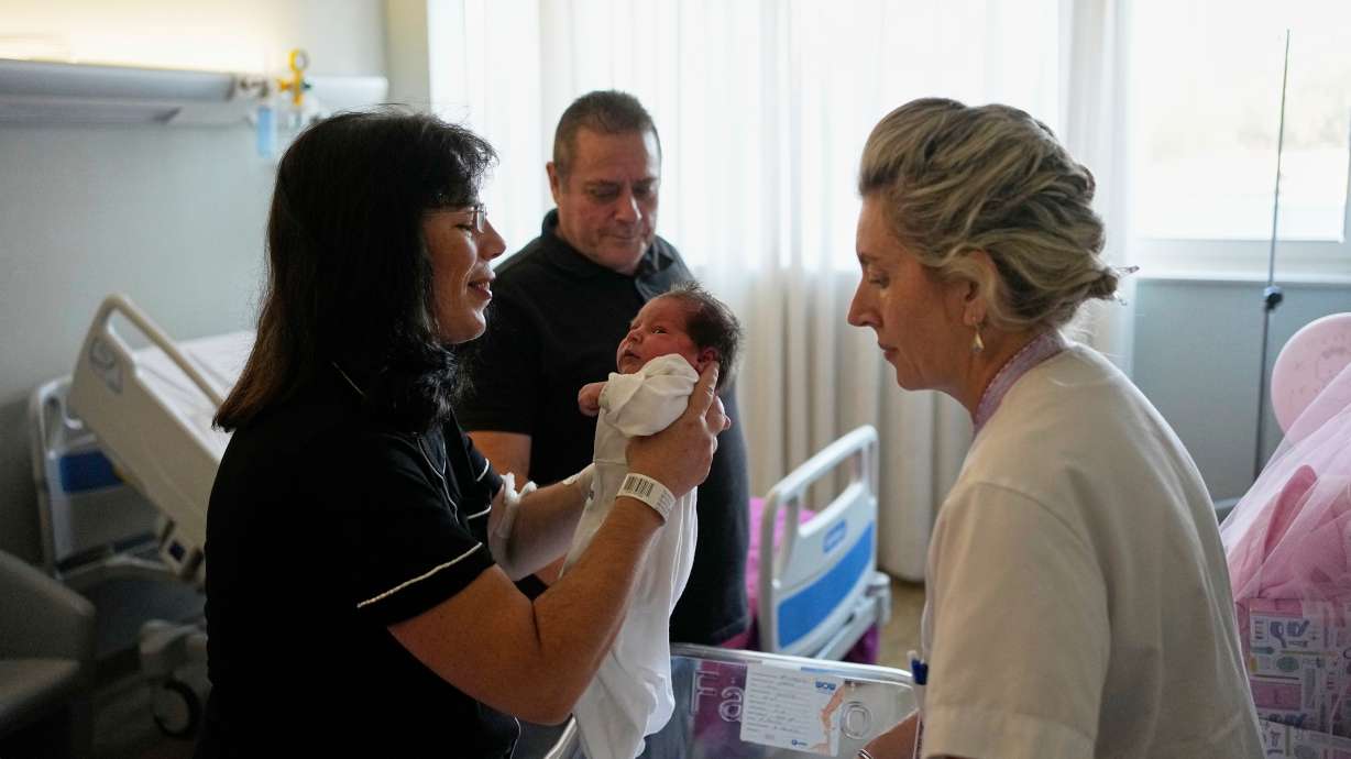 Cristina Rapti-Tzelepi, 54, holds her three-day-old daughter, Georgia, as her husband, Constantinos Raptis, 60, stands in the background at a private maternity clinic in Athens, Greece on Friday.