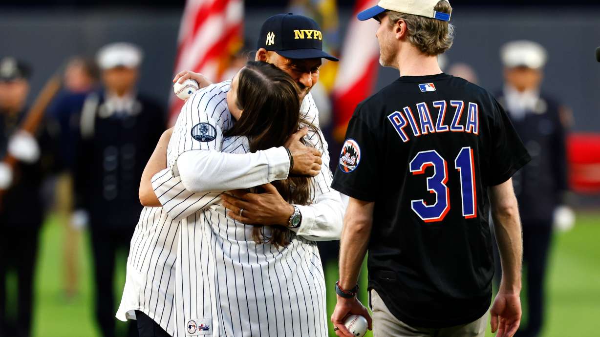 Derek Jeter hugs Brielle Saracini before she throws out the ceremonial first pitch with husband Sean McGuire before a baseball game between the New York Yankees and the New York Mets, Friday, Sept. 11, 2026, in New York.