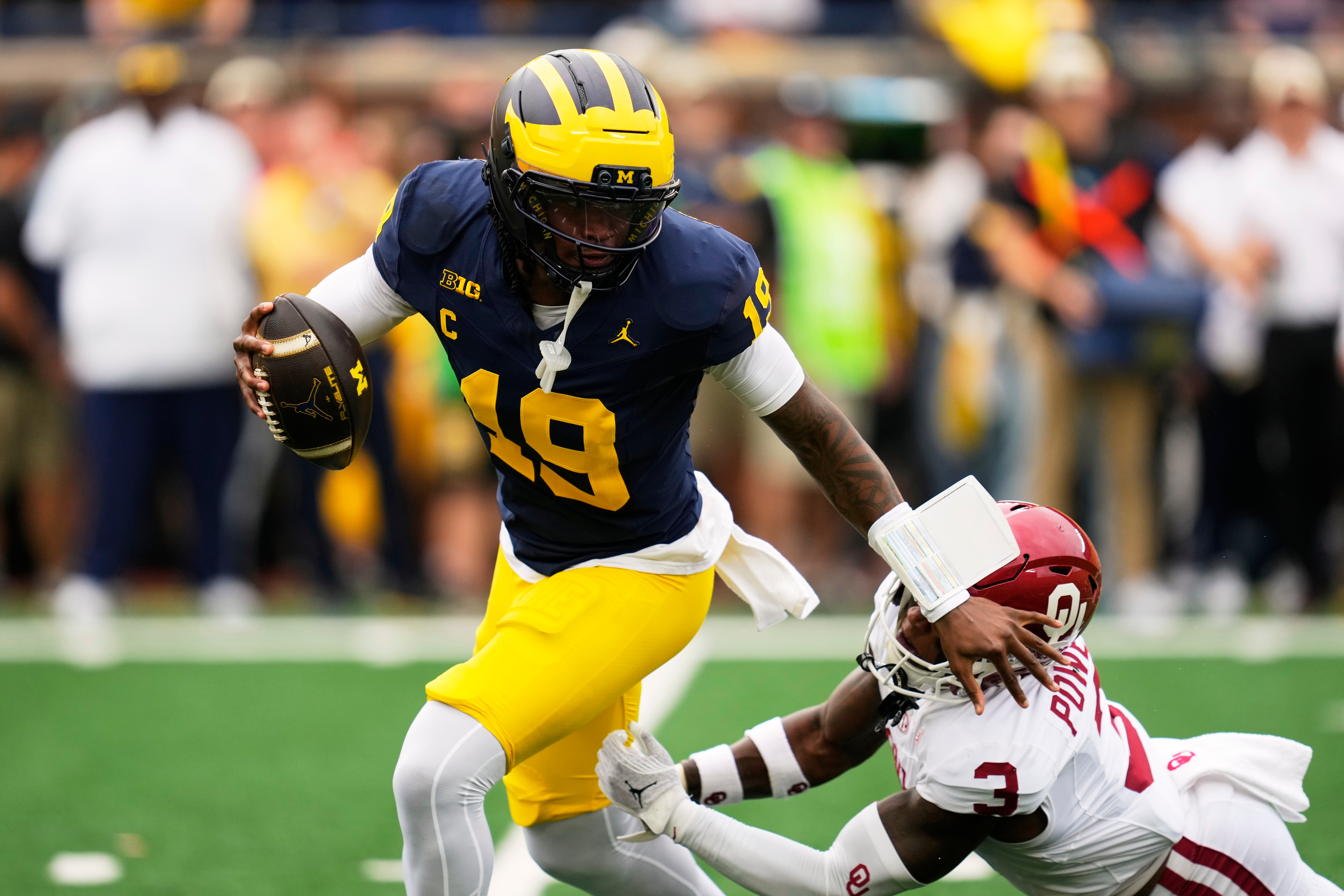 Michigan quarterback Bryce Underwood (19) escapes the tackle of Oklahoma defensive back Reggie Powers III (3) in the first half of an NCAA college football game Saturday, Sept. 12, 2026, in Ann Arbor, Mich. 