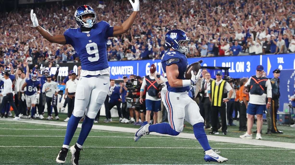 New York Giants running back Cam Skattebo, right, with teammate Isaiah Likely (9) celebrating, scores a touchdown against the Dallas Cowboys during the first half of an NFL football game Sunday, Sept. 13, 2026, in East Rutherford, N.J.