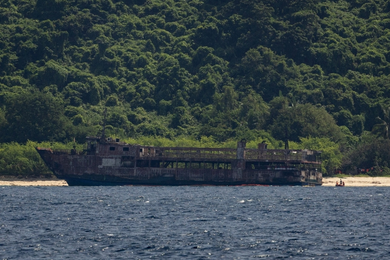 Members of the Philippine Coast Guard, in a dinghy, guard the burnt MV June Aster ferry that caught fire off the coast of Palawan, Philippines, September 13, 2026.
