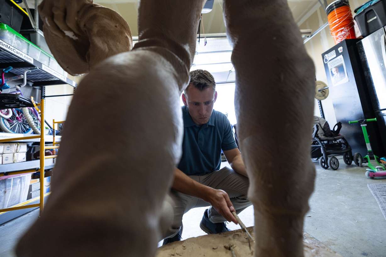 Quintin McCann works on his original clay mold of Charlie Kirk, fixing it at his home in Eagle Mountain after the bronze molding process damaged it on Monday. McCann created the statue in tribute to Kirk.
