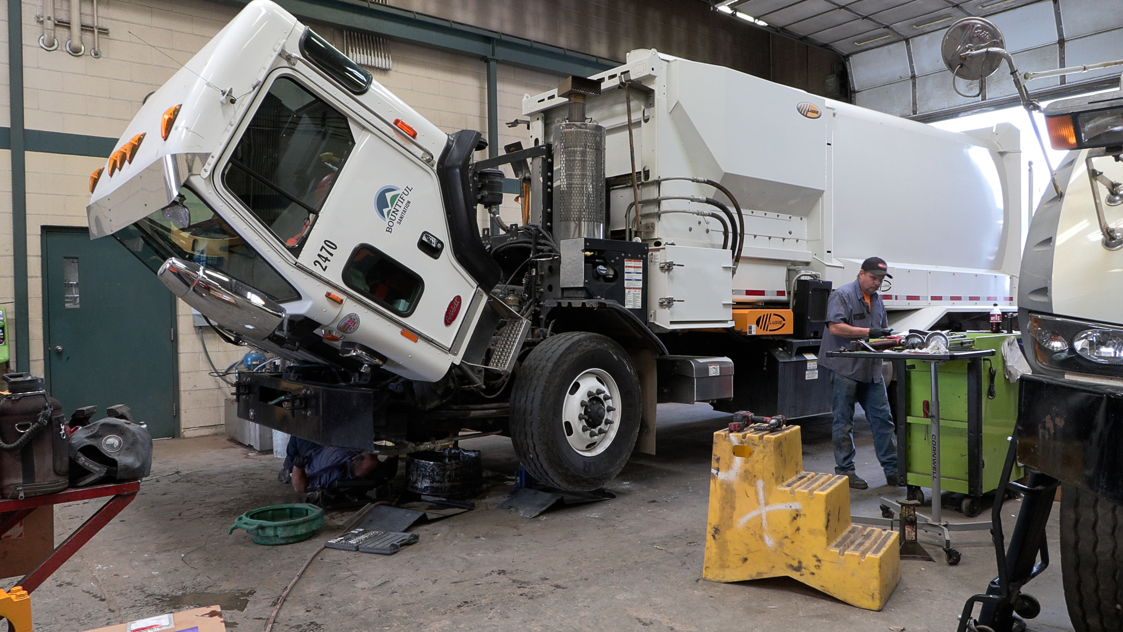 Workers repair a sanitation vehicle inside Bountiful's maintenance shop.