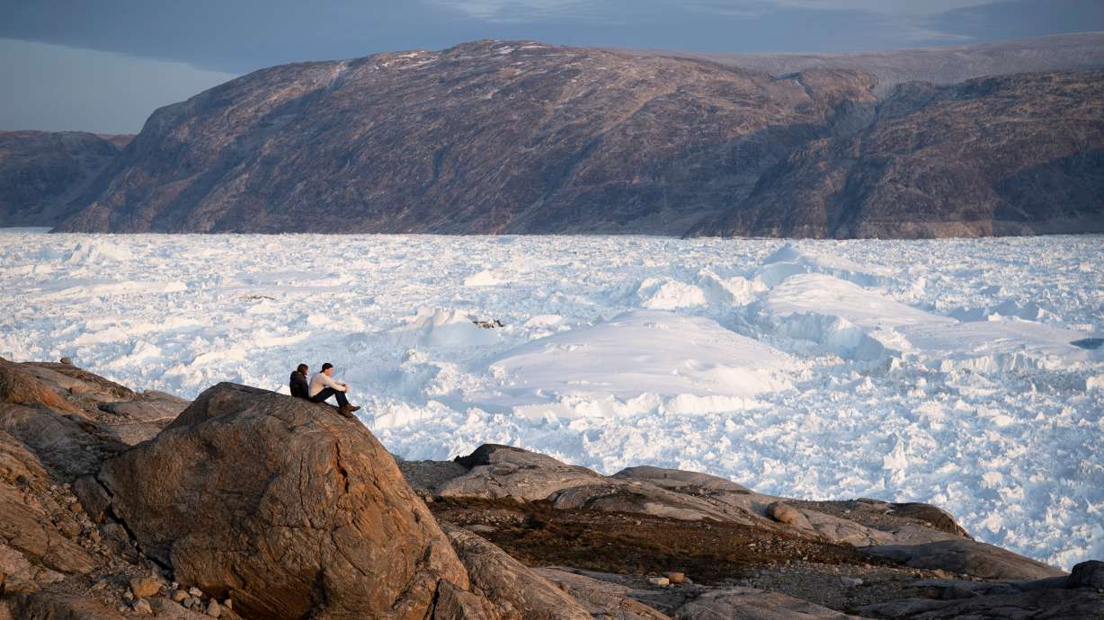 NYU student researchers sit on top of a rock overlooking the Helheim glacier in Greenland on Aug. 16, 2019. A new report finds the Earth has lost trillions of tons of ice since 1979.