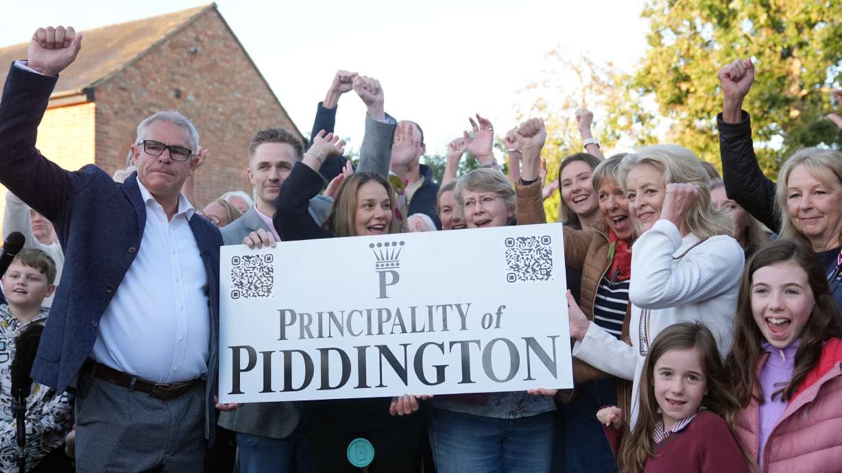 Local residents pose with a "Principality of Piddington" sign in the village of Piddington, Oxfordshire, England, Wednesday, after they voted overwhelmingly to become an independent state in a symbolic "referendum."