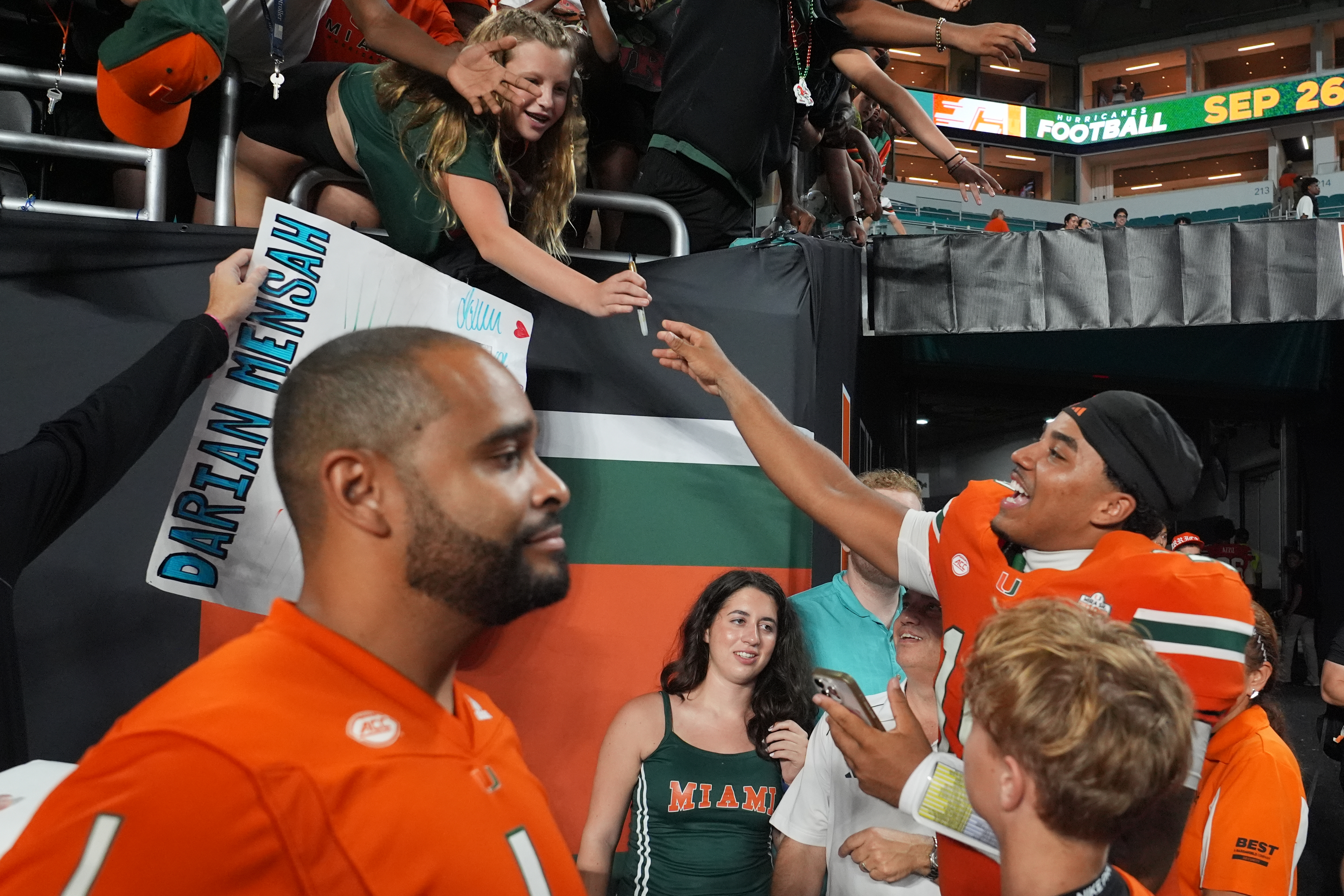 Miami quarterback Darian Mensah, right, signs autographs after an NCAA college football game against Florida A&M, Thursday, Sept. 10, 2026, in Miami Gardens, Fla. 