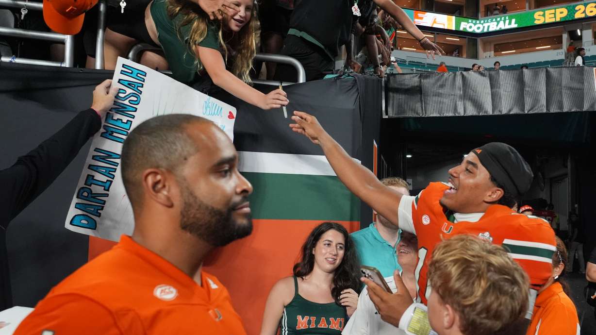 Miami quarterback Darian Mensah, right, signs autographs after an NCAA college football game against Florida A&M, Thursday, Sept. 10, 2026, in Miami Gardens, Fla.