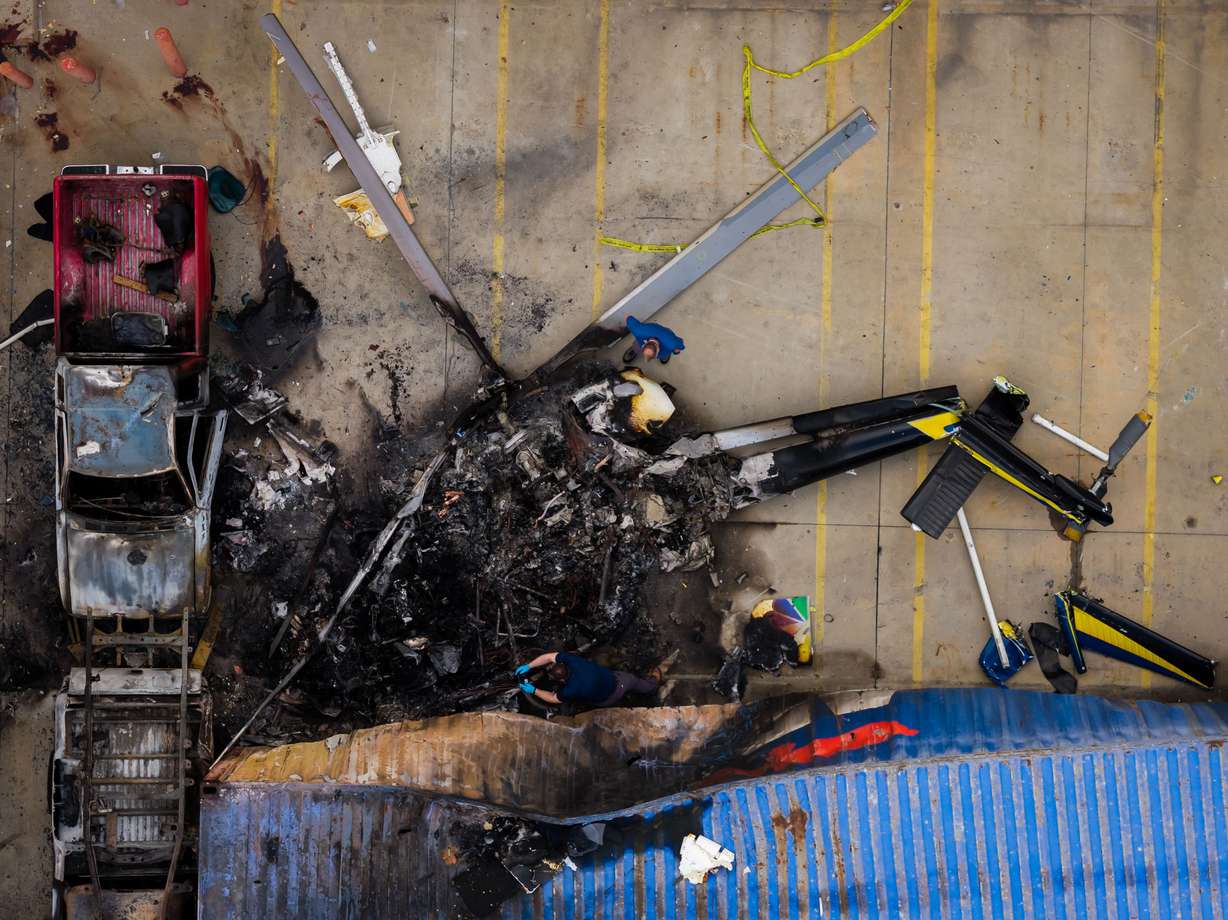 In this aerial view, people investigate the aftermath of a news helicopter crash in Chatsworth, a neighborhood in Los Angeles, on Wednesday. The crash was preceded by a collision between a bus and a car.