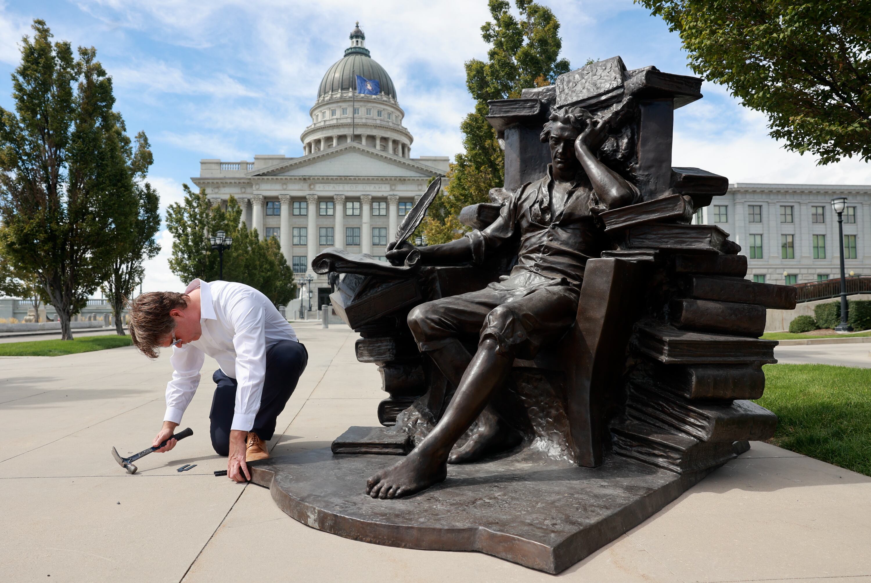 Michael Hall uses shims to level his sculpture of Thomas Jefferson outside of the Capitol in Salt Lake City on Wednesday.