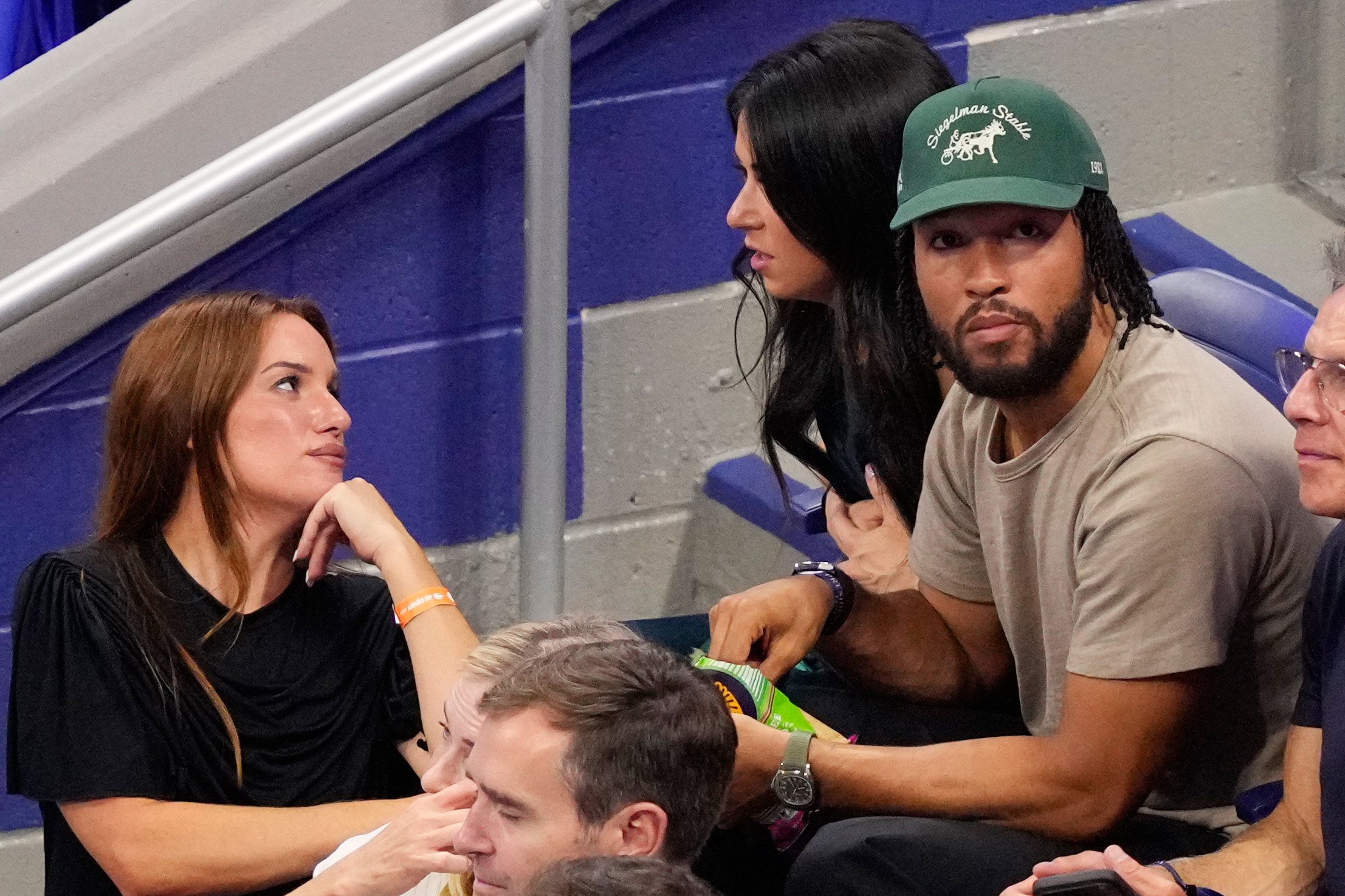 Hannah Berner, left, speaks with Ali Brunson as New York Knicks' Jalen Brunson sits next to her at a match between Ben Shelton, of the United States, and Frances Tiafoe, of the United States, during the men's singles semifinals of the U.S. Open tennis championships Friday, Sept. 11, 2026, in New York. 