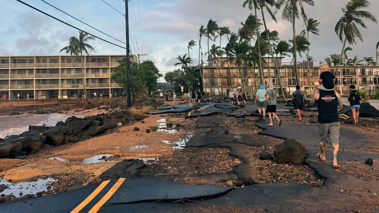 People walk past damage caused by Hurricane Lowell on Sept. 8 in Poʻipū on Kauaʻi's south shore, in Hawaii. Small businesses on the Garden Isle are asking tourists to return with aloha and patience.