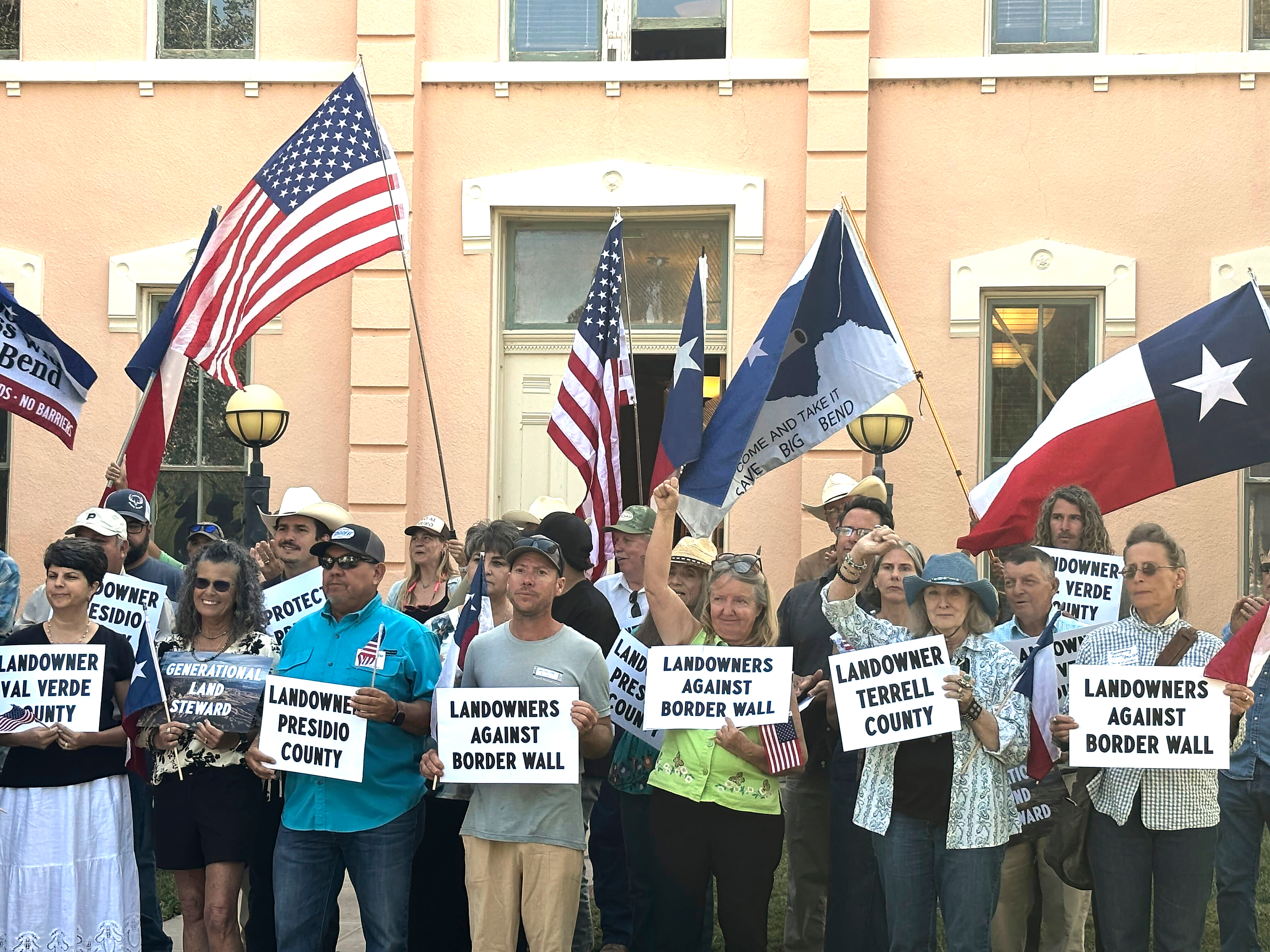 Landowners and other supporters hold signs against the Trump administration's plans to build a border wall and other infrastructure in Texas' remote Big Bend region, Monday, in Marfa, Texas. The administration began construction on Friday.