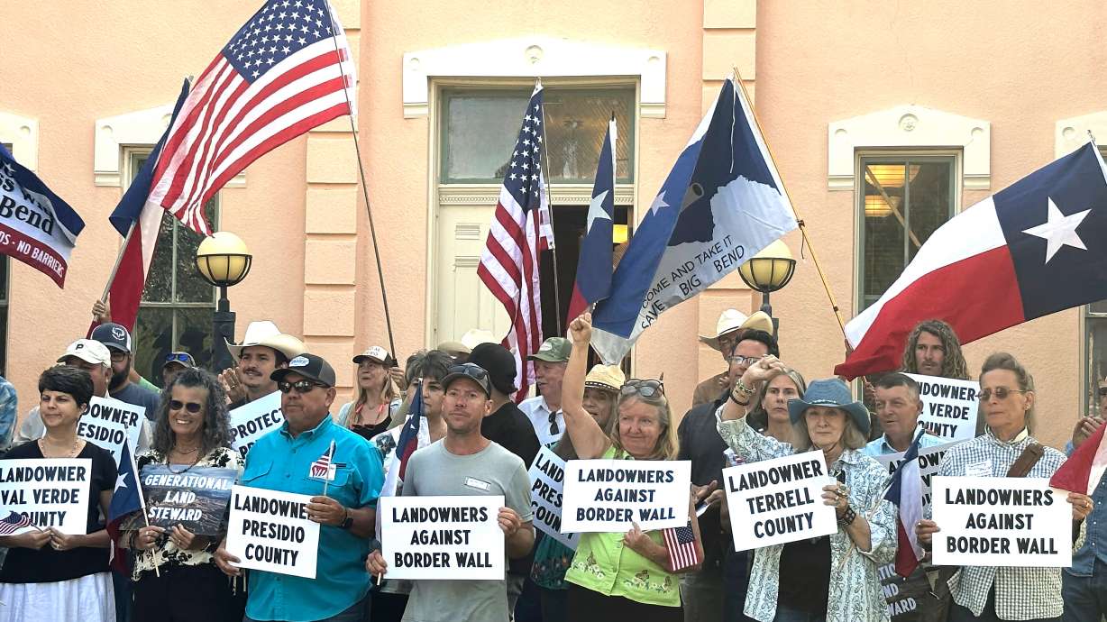 Landowners and other supporters hold signs against the Trump administration's plans to build a border wall and other infrastructure in Texas' remote Big Bend region, Monday, in Marfa, Texas. The administration began construction on Friday.