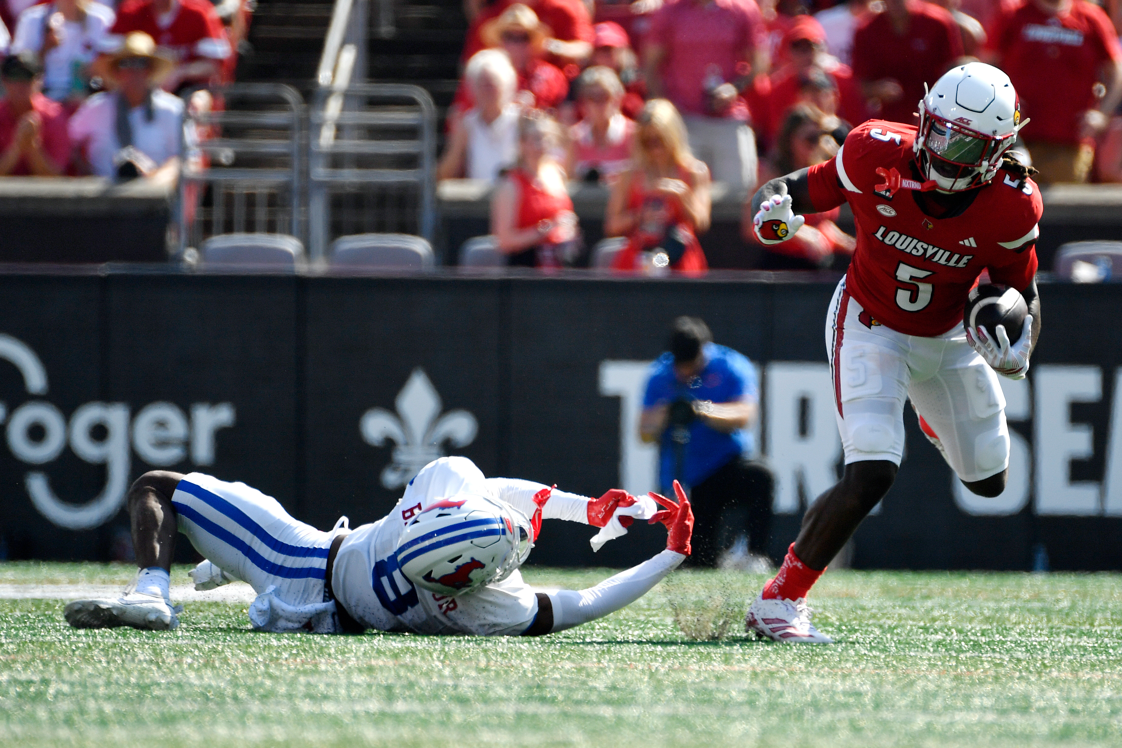 Louisville running back Keyjuan Brown (5) runs from a tackle-attempt by SMU cornerback Marcellus Barnes Jr. (8) during the first half of an NCAA college football game in Louisville, Ky., Saturday, Sept. 19, 2026. 