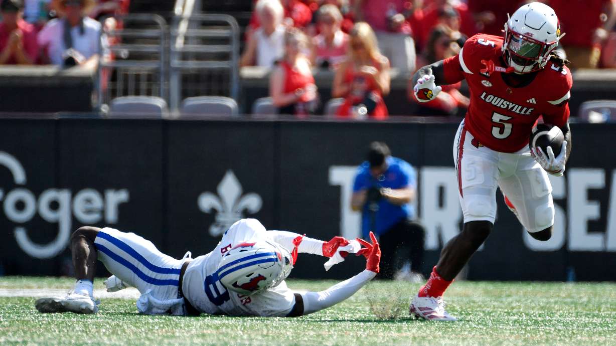 Louisville running back Keyjuan Brown (5) runs from a tackle-attempt by SMU cornerback Marcellus Barnes Jr. (8) during the first half of an NCAA college football game in Louisville, Ky., Saturday, Sept. 19, 2026.