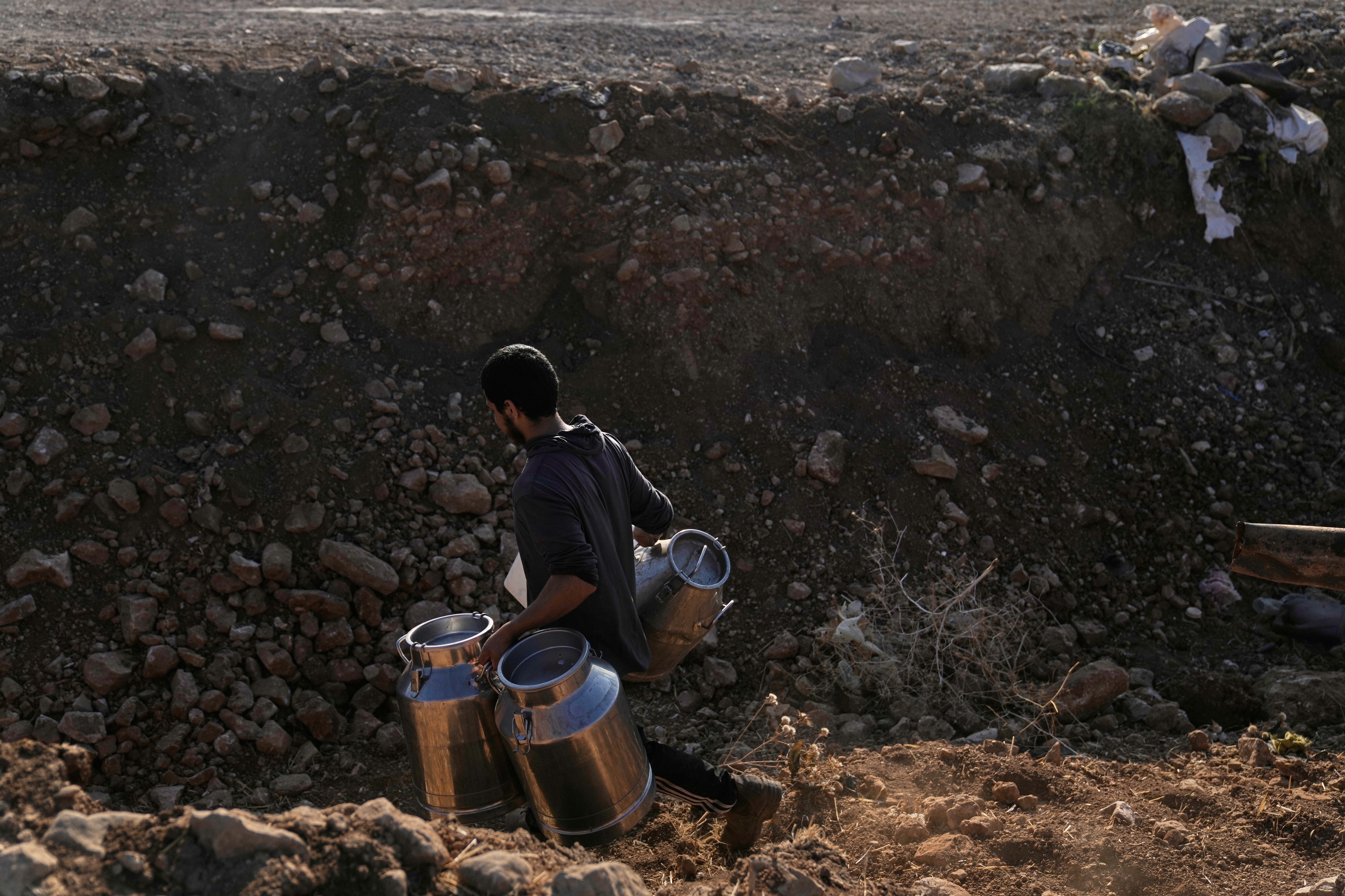 A Palestinian farmer carries containers of milk from their livestock across a trench dug by the Israeli army in a road leading to the West Bank hamlet of Khirbet Ras al-Ahmar, southeast of Tubas, on their way to sell it, Sept. 19. The U.S. is set to deport Salah Sarsour on national security concerns to the West Bank.