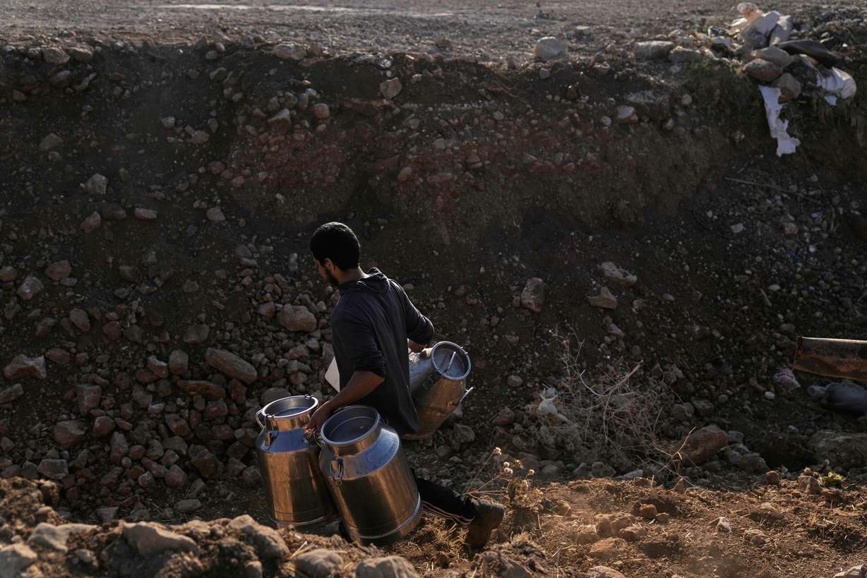 A Palestinian farmer carries containers of milk from their livestock across a trench dug by the Israeli army in a road leading to the West Bank hamlet of Khirbet Ras al-Ahmar, southeast of Tubas, on their way to sell it, Sept. 19. The U.S. is set to deport Salah Sarsour on national security concerns to the West Bank.