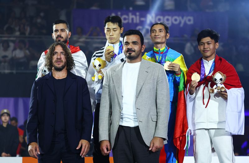 Asian Games - Aichi-Nagoya 2026 - Teqball - Higashi Sports Center, Nagoya, Japan - September 20, 2026 Olympic Council of Asia president Joaan bin Hamad Al Thani and former Spain and FC Barcelona footballer Carles Puyol during the medal ceremony as gold medallist South Korea's Lee Junsuk celebrates on the podium after winning the men's singles final along with silver medallist Iraq's Ali Jalil Mezher Alelayawi, bronze medallists Myanmar's Friday Saw and Indonesia's Yoga Ardika Putra
